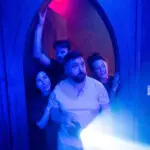 Group cautiously exploring a spooky escape room at Escapology.